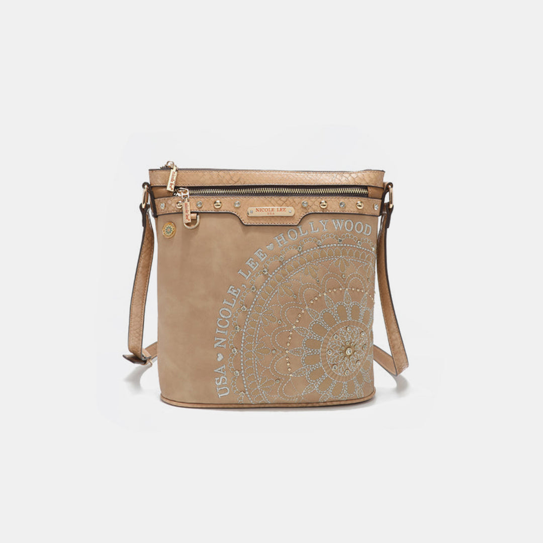 The Nicole Lee USA Metallic Stitching Embroidery Inlaid Rhinestone Crossbody Bag, crafted from vegan leather, is beige with a circular floral design and stud embellishments. It features a front zipper pocket, branded label, and gold-tone hardware for added elegance.