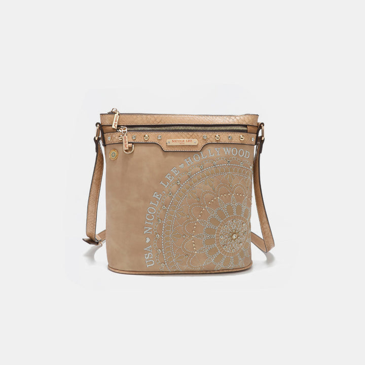 The Nicole Lee USA Metallic Stitching Embroidery Inlaid Rhinestone Crossbody Bag, crafted from vegan leather, is beige with a circular floral design and stud embellishments. It features a front zipper pocket, branded label, and gold-tone hardware for added elegance.