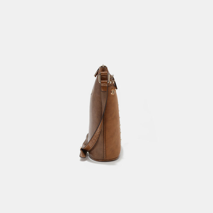Side view of the Nicole Lee USA Metallic Stitching Embroidery Inlaid Rhinestone Crossbody Bag in light brown vegan leather with a strap, zipper, and metal rings. It has a smooth texture and subtle shine, exuding simple elegance against a plain white background.