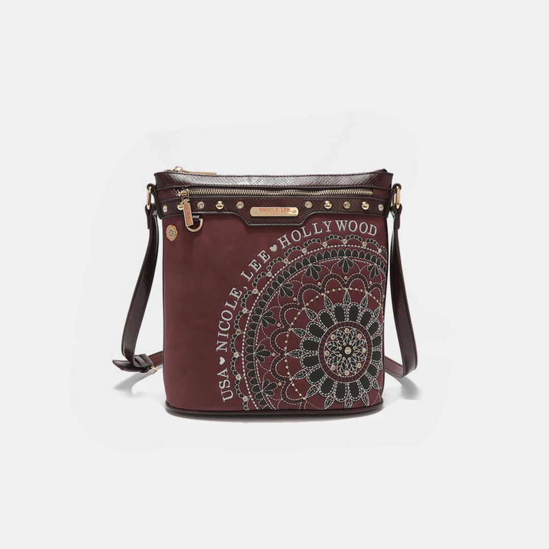 A chic maroon Nicole Lee USA crossbody bag with a circular mandala pattern, rhinestone details, made from vegan leather. It features a zippered top, adjustable strap, and Nicole Lee USA Hollywood text on the side.