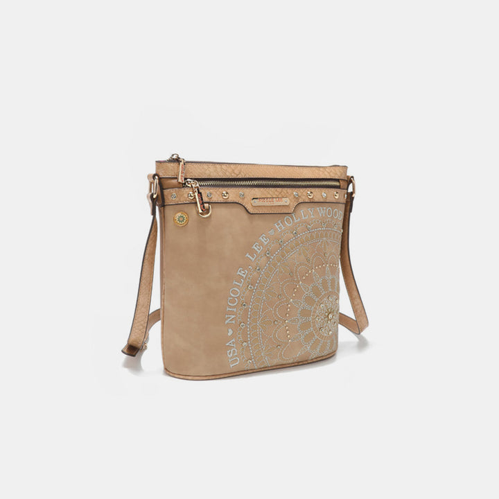The Nicole Lee USA Metallic Stitching Embroidery Inlaid Rhinestone Crossbody Bag is a beige vegan leather accessory featuring a mandala design with Nicole Lee USA Hollywood text, a zippered top, metallic accents, an adjustable strap, and a plain light background.