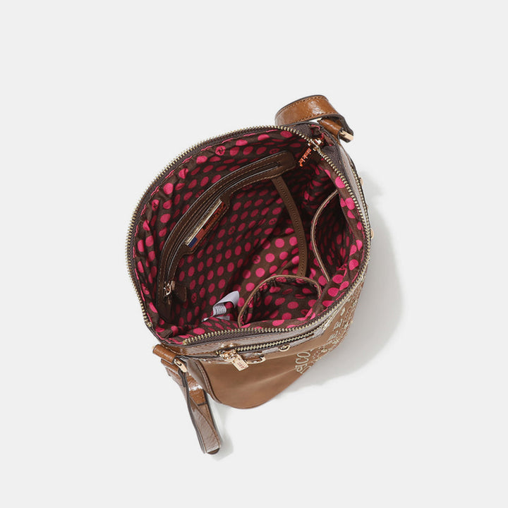 A top view of the open Nicole Lee USA Metallic Stitching Embroidery Inlaid Rhinestone Crossbody Bag in brown vegan leather shows a patterned red and black polka dot interior. The bag has multiple compartments, is empty, with a partially open zipper and two side handles visible.